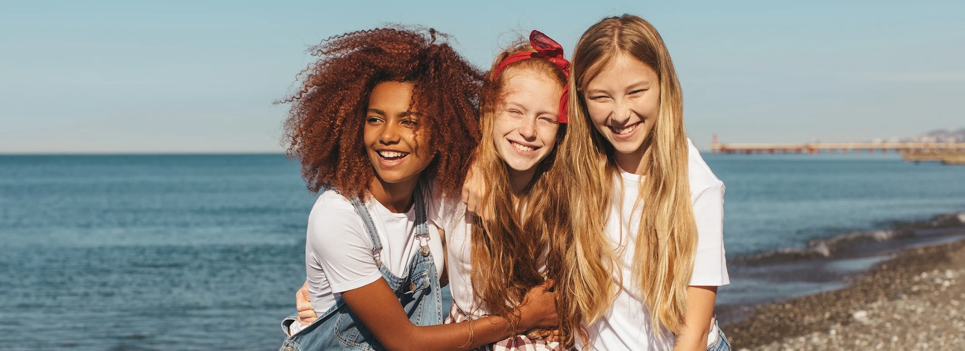 three diverse girls smiling on a beach